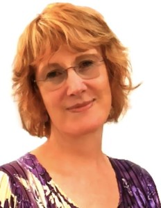 Head-and-shoulders photograph of woman with short red hair, wearing a purple-patterned garment