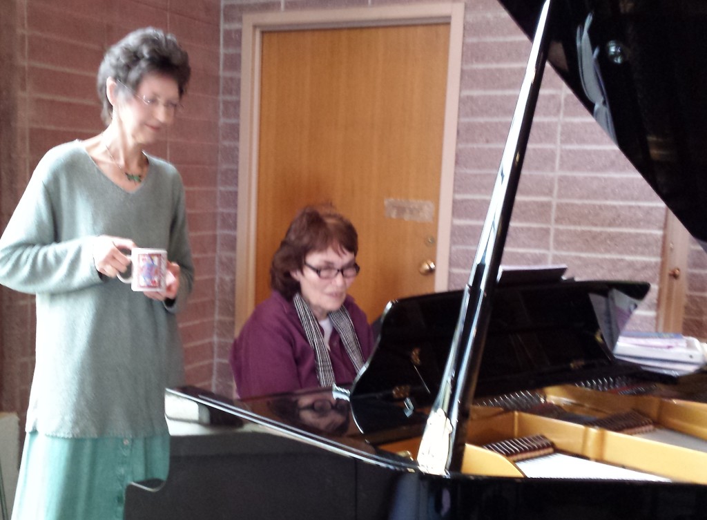 Jane Manning sits at RVUUF piano as Shaun Garner, standing behind her, looks on