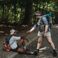 reaching hand out to help hiker get back up and keep going